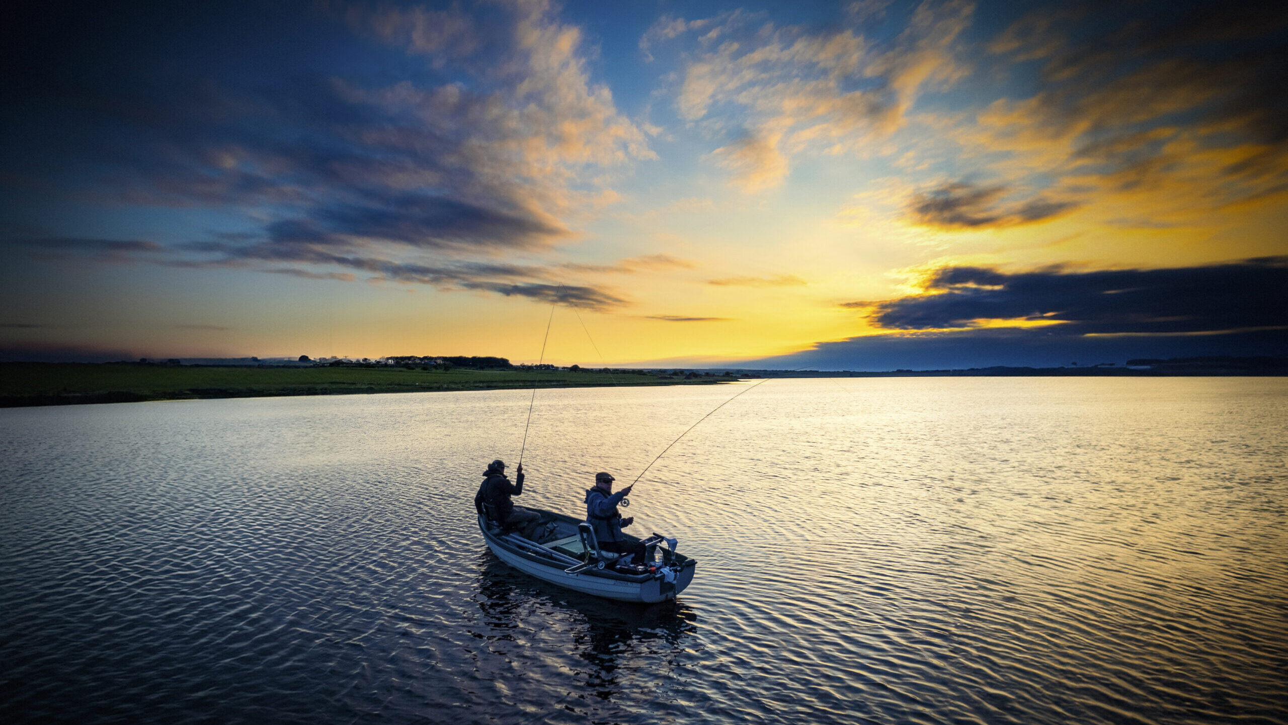 Two men on a boat out on a lake fishing