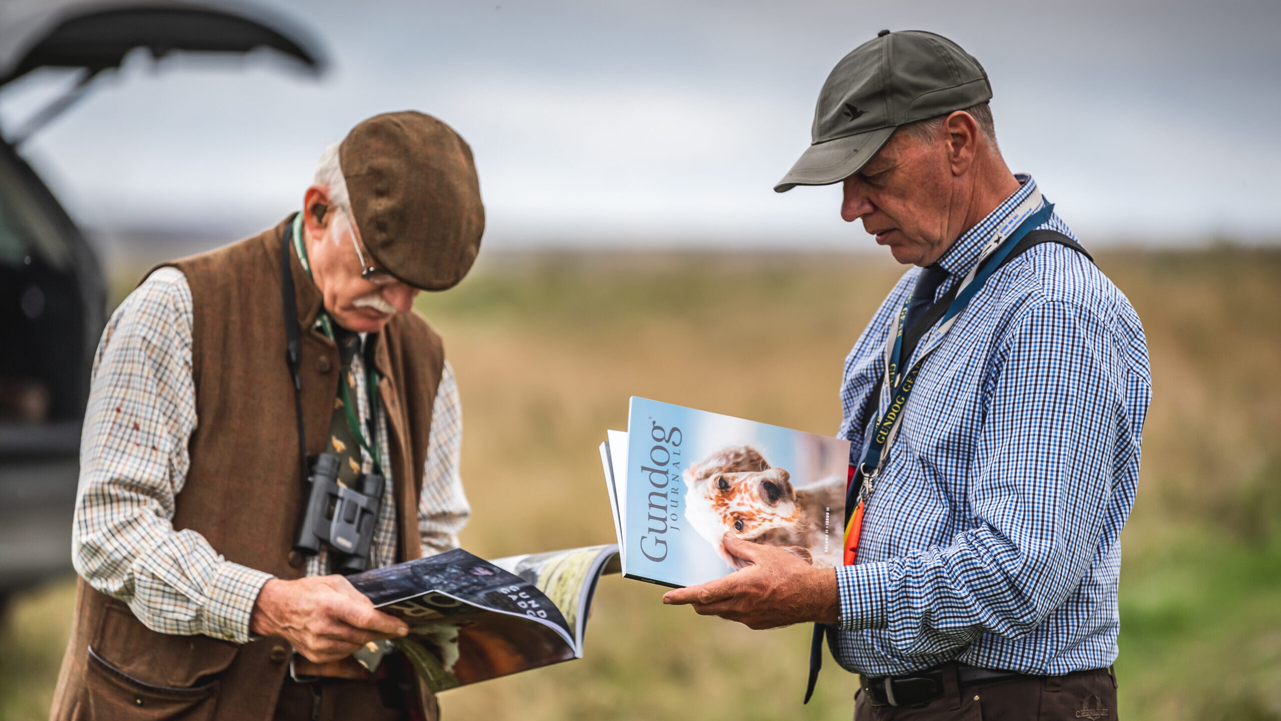 Two men out in the field reading copies of Gundog Journal