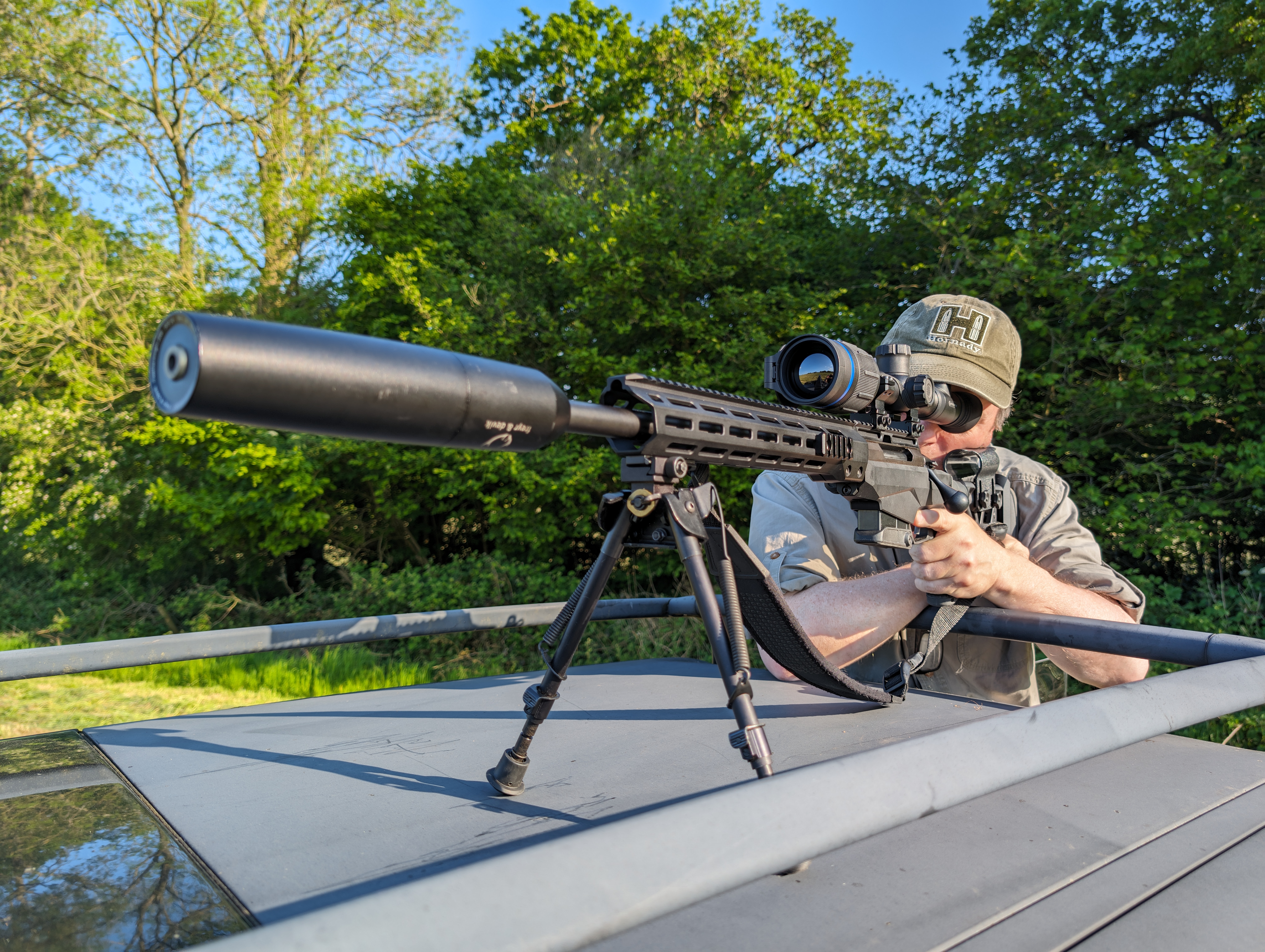 Man shooting rifle using the roof of his truck as a stand