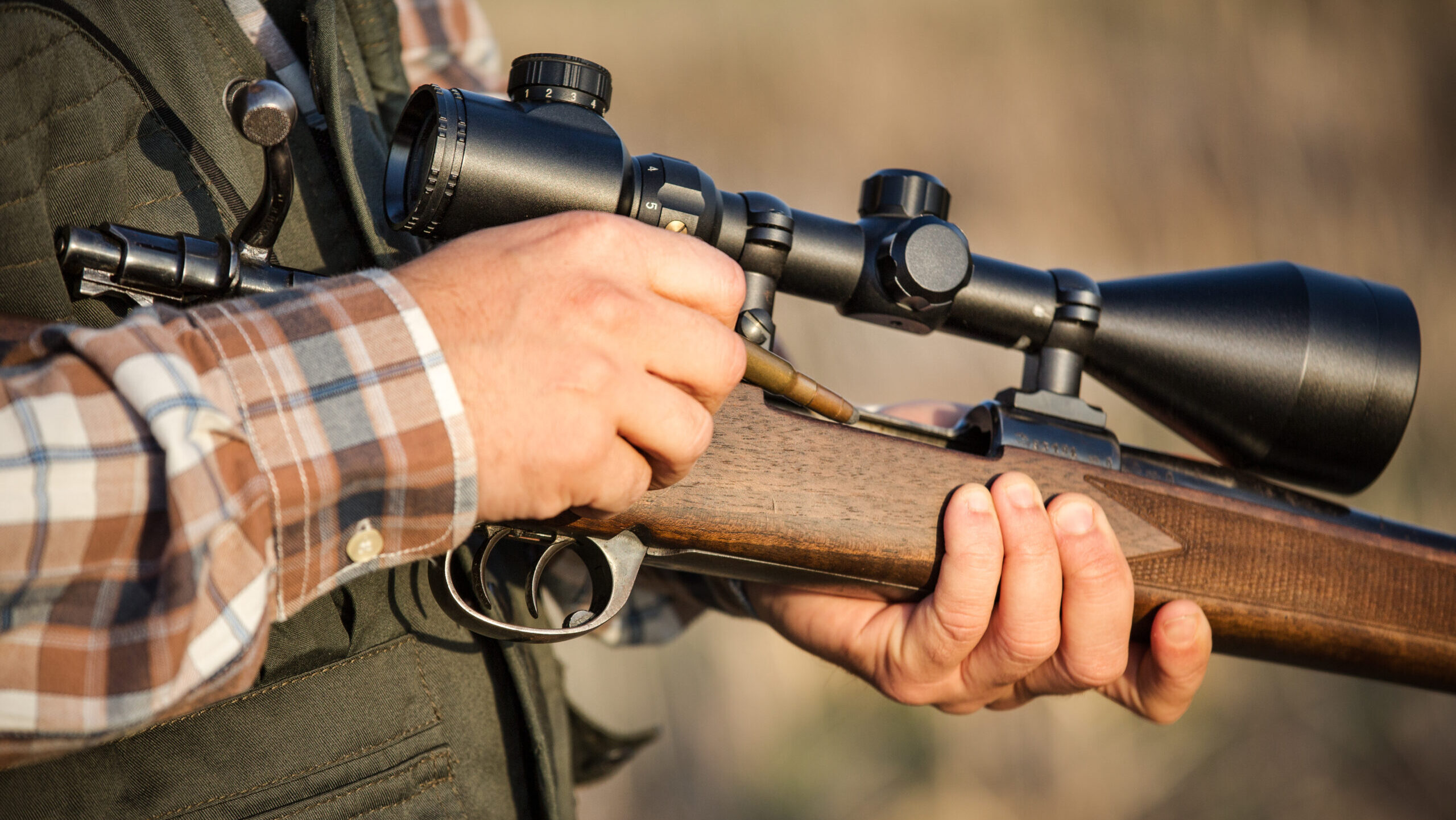 Man loading bullet into chamber of rifle
